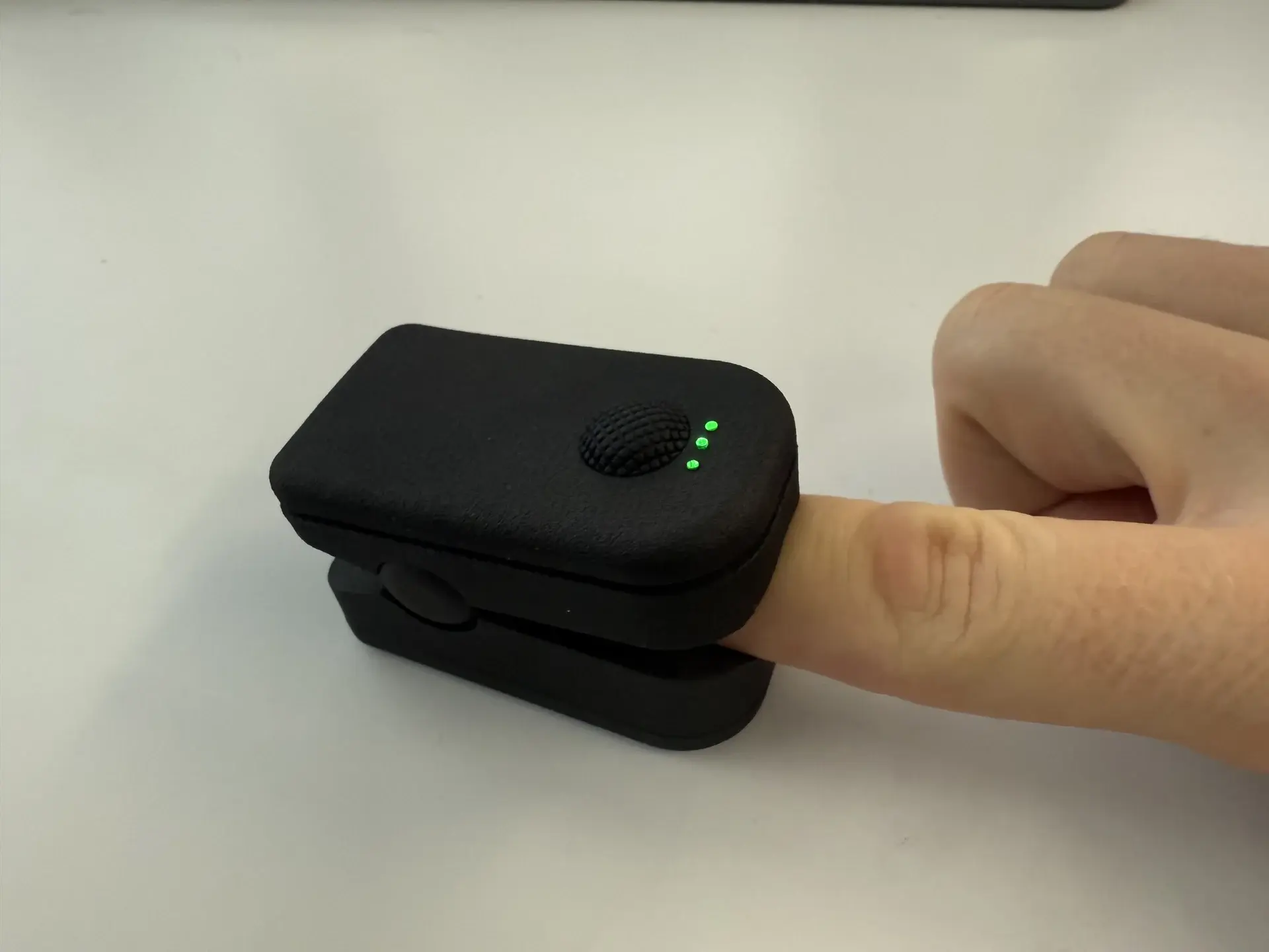 PPG sensor on a finger with active green measurement LEDs, closed housing in SpO2 clip design