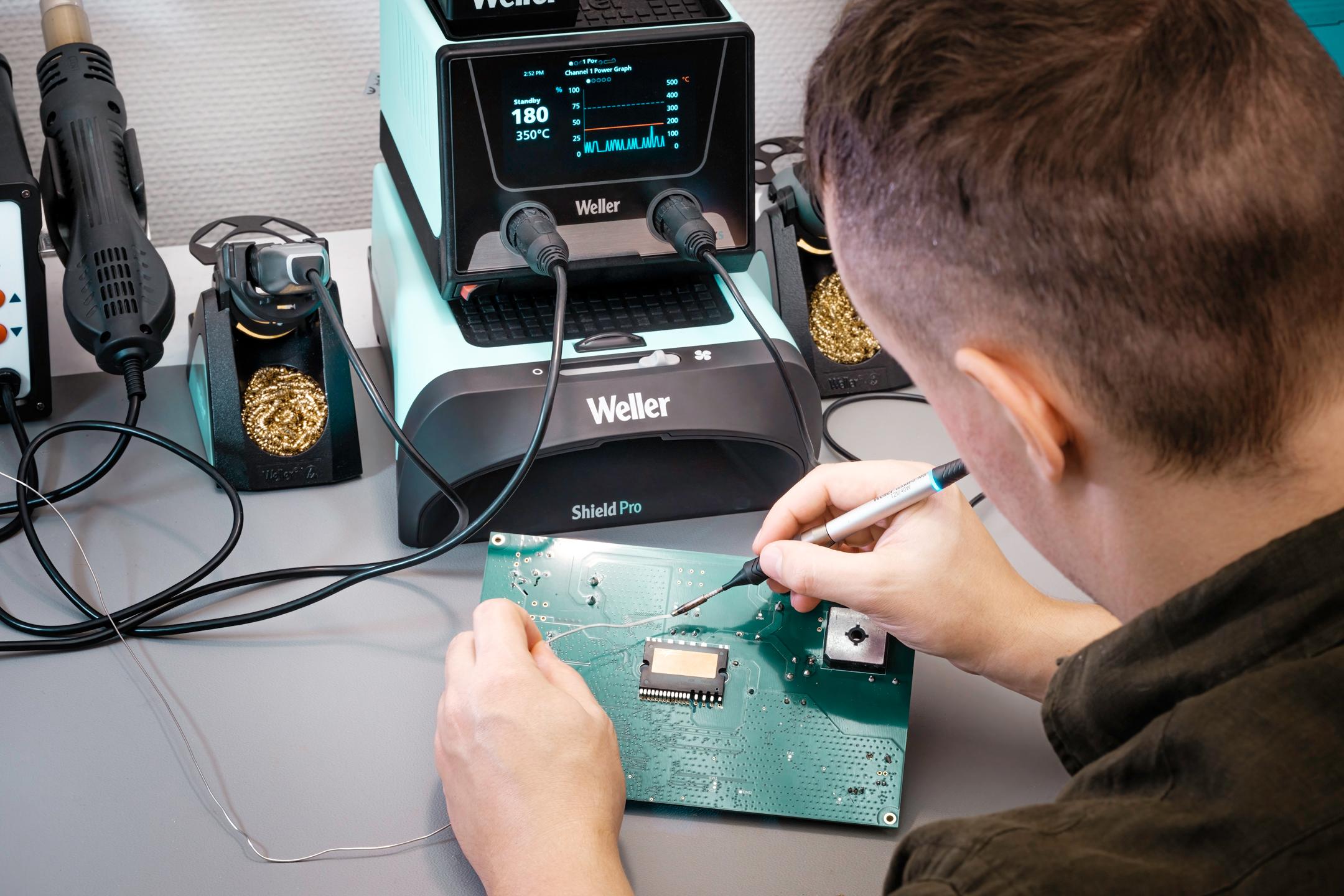 Engineer soldering a circuit board using a professional Weller Shield Pro soldering station at the Akrodyn lab in Zurich.