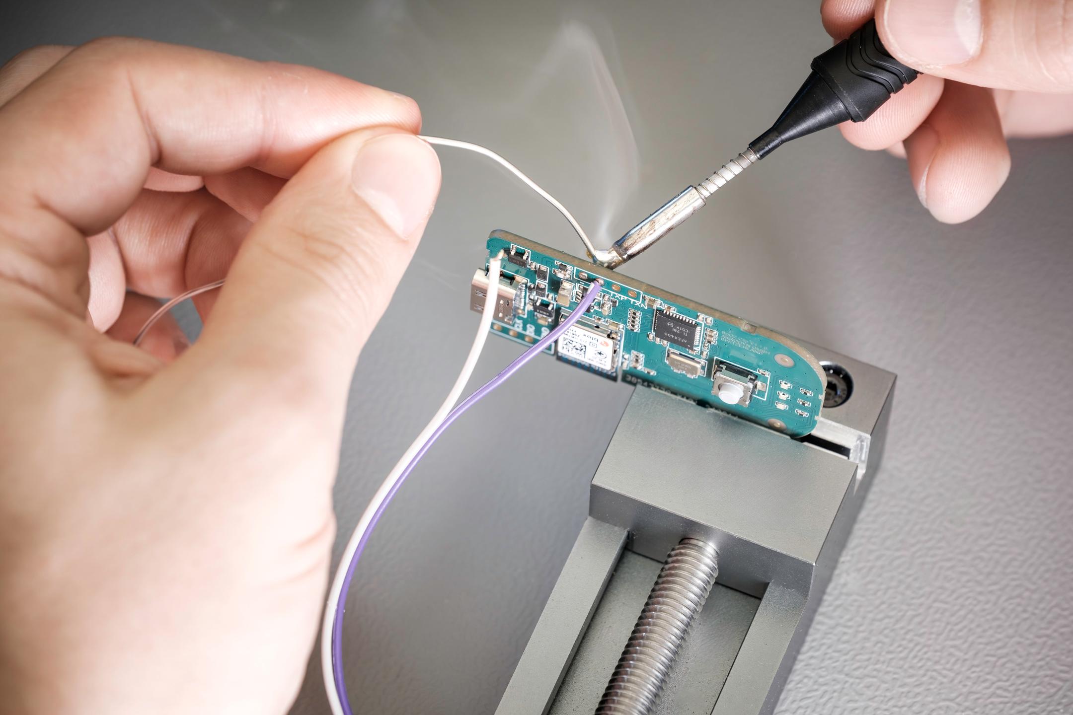 Hands soldering with smoke rising