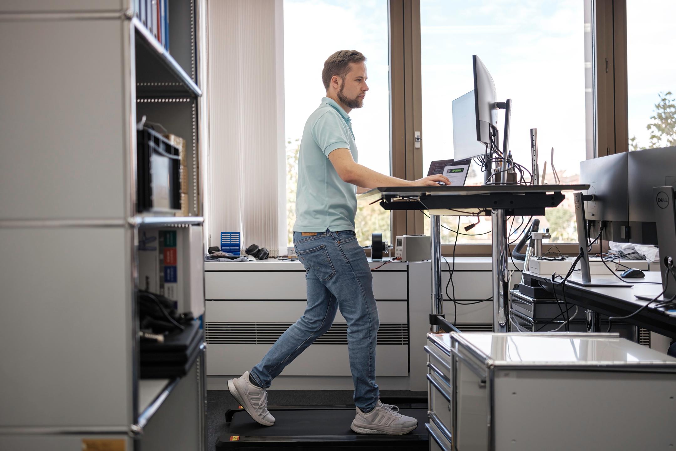 Team member at a standing desk with treadmill at Akrodyn office